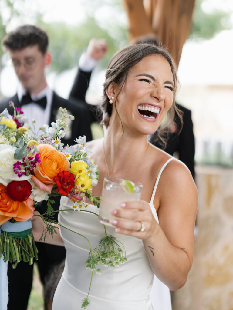 Bride laughing with her colorful bouquet during an Austin wedding celebration