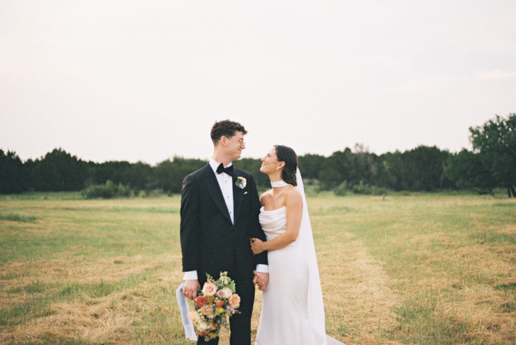 Bride and groom standing together in an open field after their Austin wedding ceremony