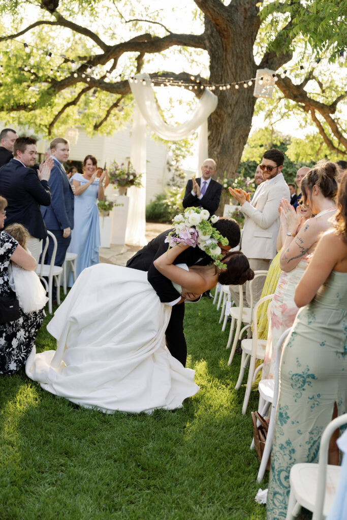 Bride and groom sharing a dip kiss during an outdoor Austin wedding ceremony