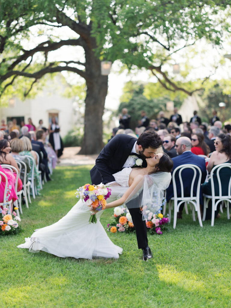 Amanda and Sean sharing their first kiss during their outdoor wedding ceremony at Barr Mansion in Austin.