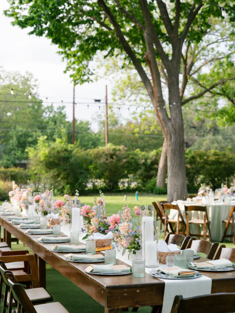 Long outdoor reception tables with colorful floral arrangements on the lawn at Woodbine Mansion.
