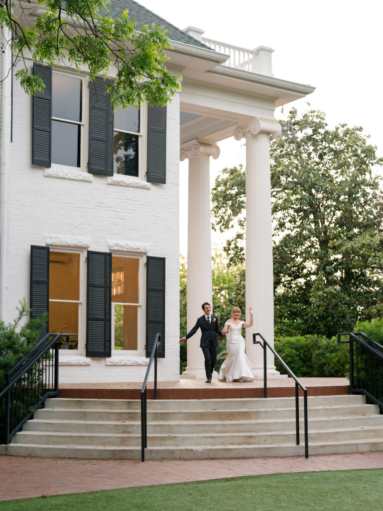 Newlyweds stepping outside the grand entrance of Woodbine Mansion after their wedding.