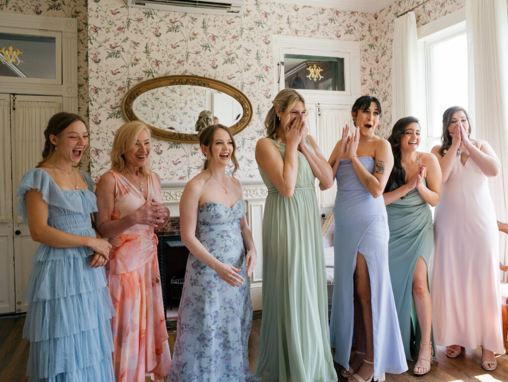 Bridesmaids reacting joyfully as they see the bride inside Woodbine Mansion before the wedding ceremony.